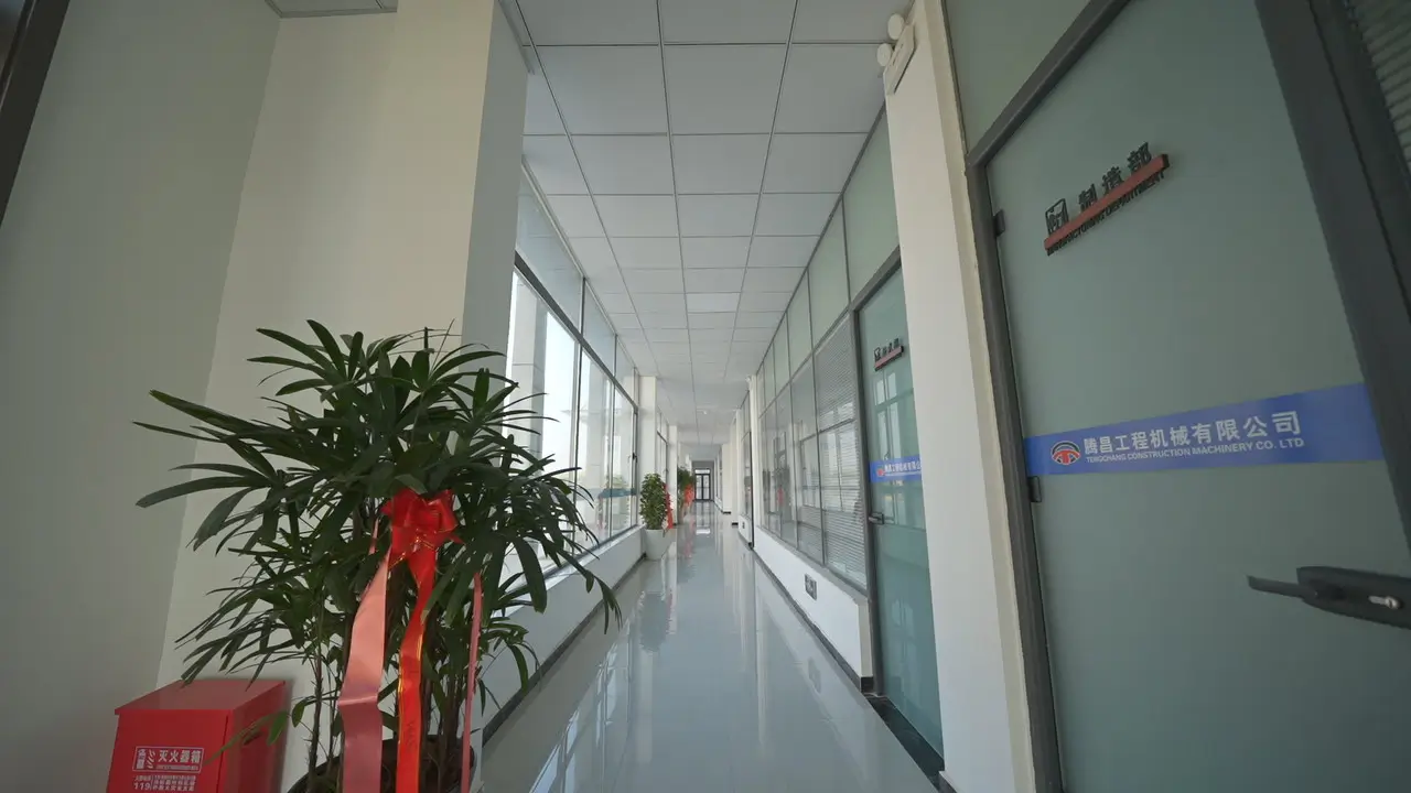 Interior corridor of the modern office building at zory Construction Machinery Co. Ltd, brightly lit, leading towards the Manufacturing Department office, showing a clean and professional environment.