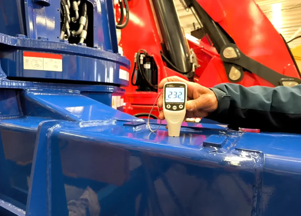 In our production facility, a technician carefully inspects the blue paint thickness of a 5 ton truck mounted crane, a crucial step for ensuring the crane's durability and appearance. This crane could also be referred to as a 5 ton crane truck.