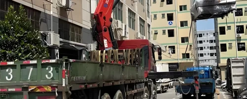 Customer using a red truck mounted knuckle boom crane (knuckle crane truck) for material handling (moving loads) in a city environment with buildings. This showcases the functionality of a truck loader crane in logistics or construction applications.